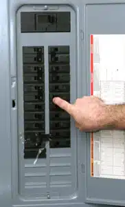man pointing too circuit breaker on an electrical panel